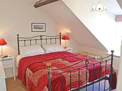 ウェルス・ネクスト・ザ・シーにあるWherry Cottageのベッドルーム1室(赤毛布付きの大型ベッド1台付)