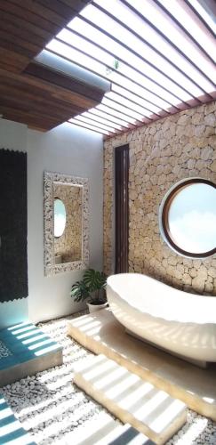 a bathroom with a large white tub and two mirrors at casa idea ubud in Ubud