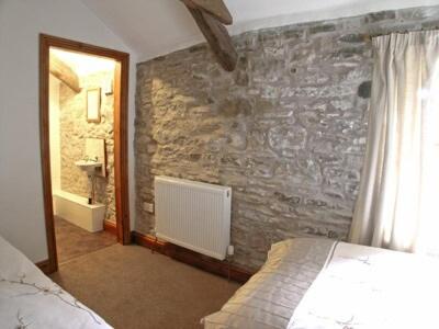a bedroom with a stone wall with a bed and a mirror at Lord Mayors Barn in Alston
