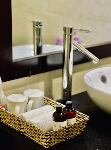 a bathroom with a sink and a basket with two bottles at Pearl Beach Homestay - Cua Dai Beach, Hoi An in Hoi An
