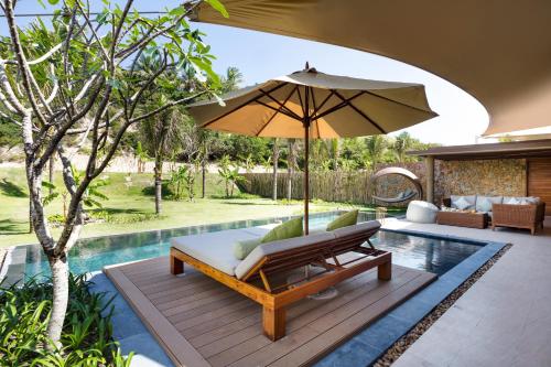 an umbrella sitting on a deck next to a pool at Fusion Resort Cam Ranh - All Spa Inclusive in Cam Ranh