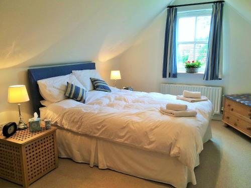 a bedroom with a large white bed with a window at Bumble Cottage in Newton on the Moor
