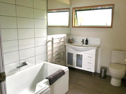 a bathroom with a tub and a sink and a toilet at Panoramic Views - House in Ahipara