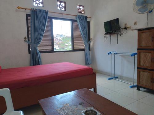 Una habitación con dos camas y una mesa y una ventana. en Wisma Galiharum Banjarnegara, en Banjarnegara