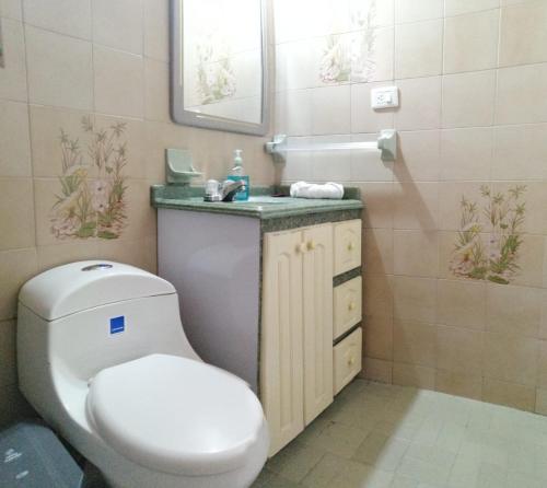 a bathroom with a toilet and a sink and a mirror at Como en casa in Bogotá