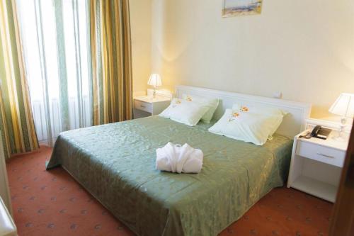 a hotel room with a bed with two towels on it at Laetu in Atyraū