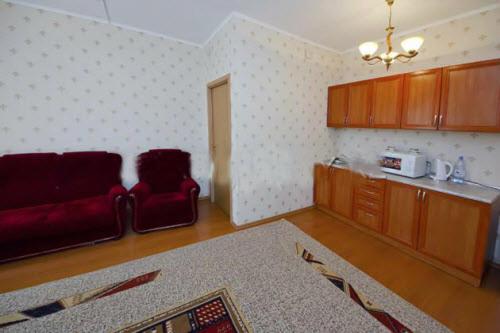 a living room with a red couch and a kitchen at Laetu in Atyraū