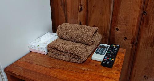 a wooden table with a remote control and a chair at ペンションやいま日和 in Ishigaki Island