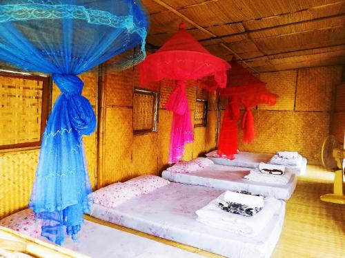 vier bedden in een kamer met blauwe en rode gordijnen bij Baan 2 Dao Farmstay in Chiang Dao