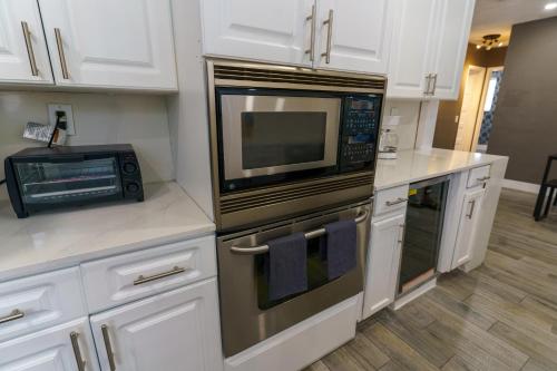 una cocina con electrodomésticos de acero inoxidable y armarios blancos en Metaverse Manor Hardrock Stadium, en Miramar