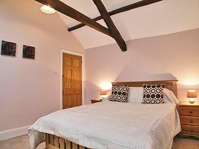 a bedroom with a large bed and a wooden ceiling at Well Cottage in Luxborough