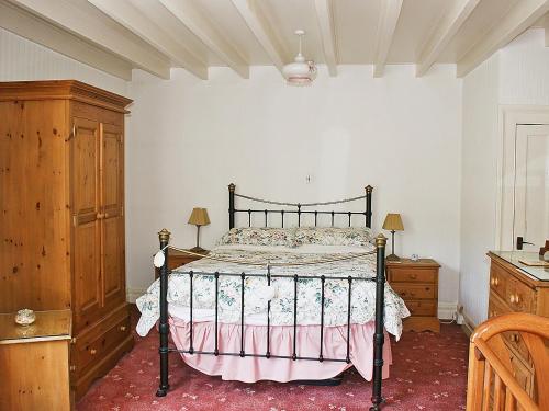 ロビン・フッズ・ベイにあるFlagstaff Cottageのベッドルーム1室(ベッド1台付)、木製キャビネットが備わります。