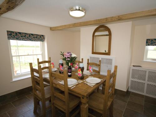 uma sala de jantar com uma mesa de madeira e cadeiras em Somer Leyton Cottage em Chapel Saint Leonards