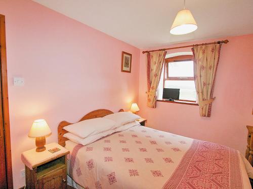 a bedroom with a bed with pink walls and a window at Beech Lodge in Buckland Brewer