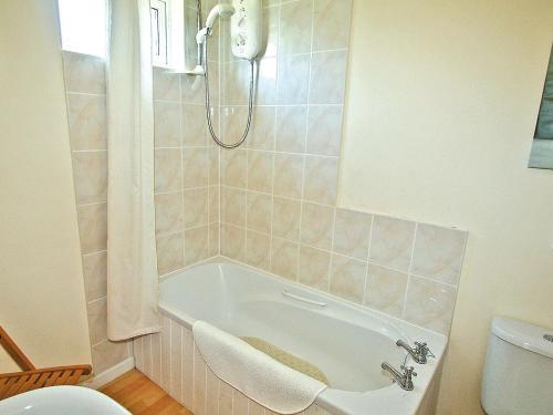 a bathroom with a bath tub and a toilet at Poppy - 28865 in Stokeinteignhead
