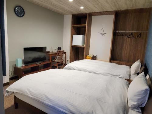 a bedroom with two beds and a tv and a desk at First Inn Takamatsu in Takamatsu
