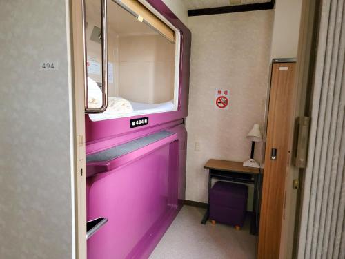 une porte rose dans une chambre avec fenêtre dans l'établissement First Inn Takamatsu, à Takamatsu