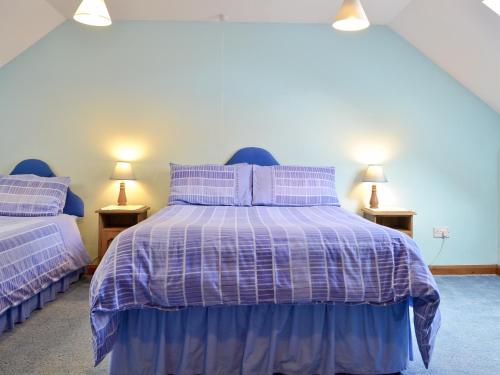 a bedroom with a purple bed with two lamps at Craneham Court in Buckland Brewer