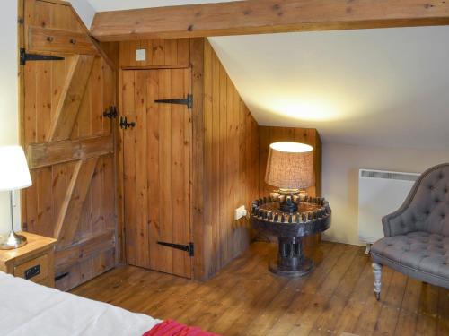 a bedroom with a wooden wall with a table and a lamp at The Old Stable in Edale
