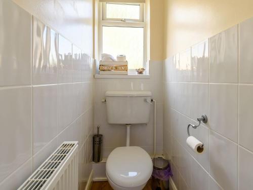 a white bathroom with a toilet and a window at Lilac Studio in Wheldrake