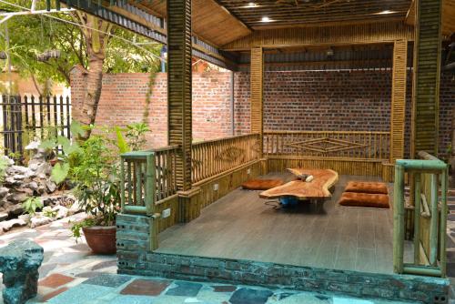 a patio with a table and benches and a brick wall at City Garden Hostel in Ninh Binh