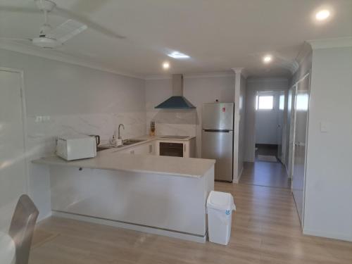 a white kitchen with a sink and a refrigerator at Markwell St Villas in Kingaroy