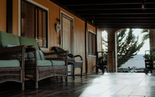 an outdoor porch with wicker chairs and a door at Cabaña R y A Valle de Guadalupe in Valle de Guadalupe