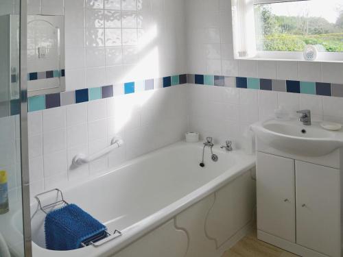 a white bathroom with a tub and a sink at Goonlaze in St Austell