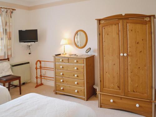 a bedroom with a wooden cabinet and a dresser at Goonlaze in St Austell