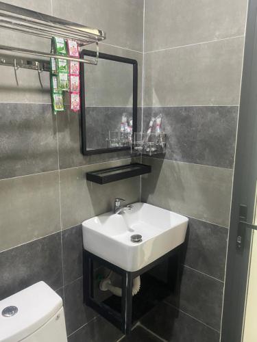 ein Badezimmer mit einem Waschbecken, einem Spiegel und einem WC in der Unterkunft Hotel Hòa Bình in Bình Châu