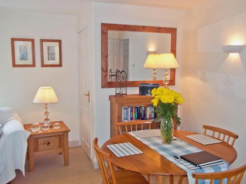 a dining room with a table with a vase of flowers on it at Cobble Stones in Holt