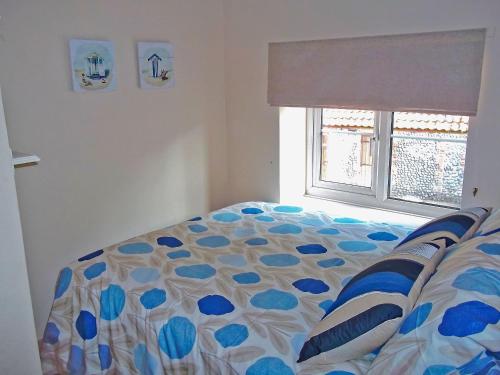 a bedroom with a bed and a window at Cobble Stones in Holt