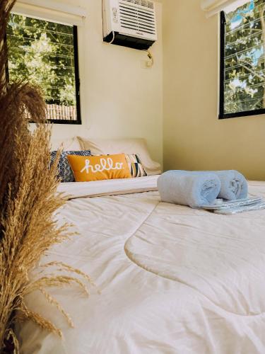 1 cama blanca grande en una habitación con 2 ventanas en Hideaway Cabins en Batangas