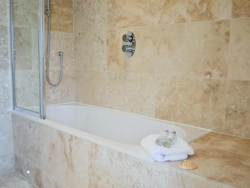 y baño con ducha, bañera y toallas. en Gylly Beach View - Tor, en Falmouth