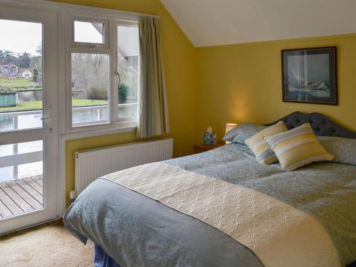 a bedroom with a bed and a large window at The Wherry in Wroxham