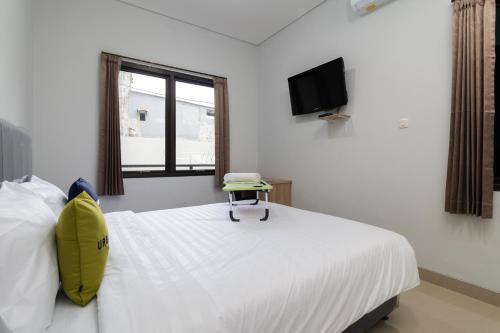 - une chambre avec un lit doté d'un oreiller jaune dans l'établissement Urbanview Hotel Pasar Baru Jakarta by RedDoorz, à Jakarta