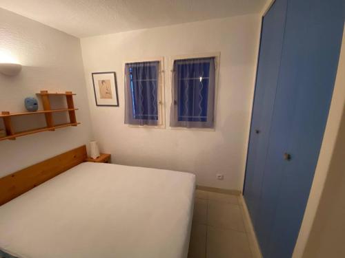 - une chambre avec un lit blanc et 2 fenêtres dans l'établissement T2 cabine 6 pers, piscine, parking, animaux admis - FR-1-81-467, au Barcarès