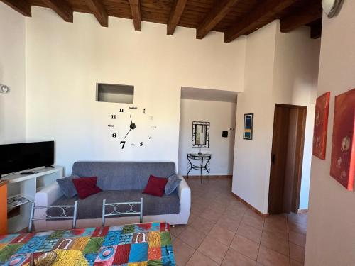 Casa Vacanze A' Lanterna في ليكاتا: غرفة معيشة مع أريكة وساعة على الحائط