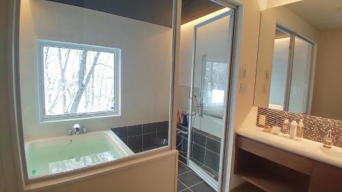 a bathroom with a bath tub and a window at White Tree Lodge Madarao Tangram in Shinano
