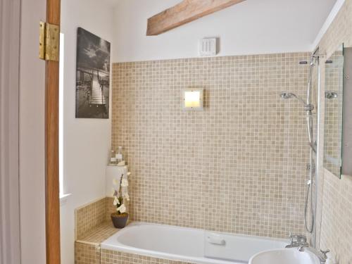 a bathroom with a tub and a tiled wall at Beach View in Bamburgh