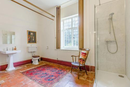een badkamer met een douche, een stoel en een wastafel bij The Generals Quarters in Shrewsbury