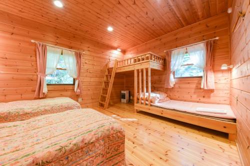 Dormitorio en cabaña de madera con 2 camas y ventanas en Shurin, en Tsumagoi