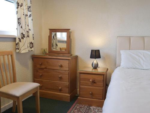 a bedroom with a bed and a dresser with a mirror at Arforwest in Llangranog