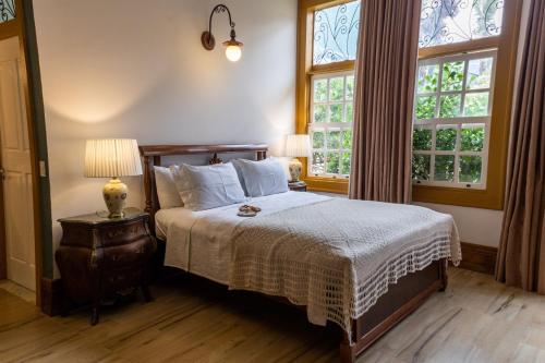 um quarto com uma cama e duas janelas em Pousada Pequena Tiradentes em Tiradentes