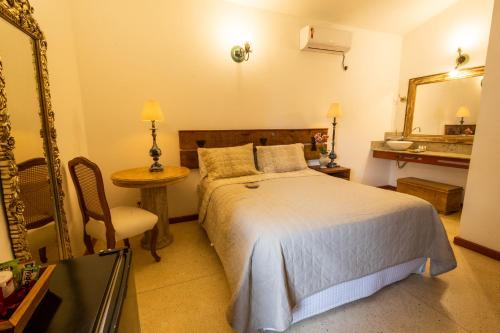 a bedroom with a bed and a mirror and a table at Pousada Pequena Tiradentes in Tiradentes