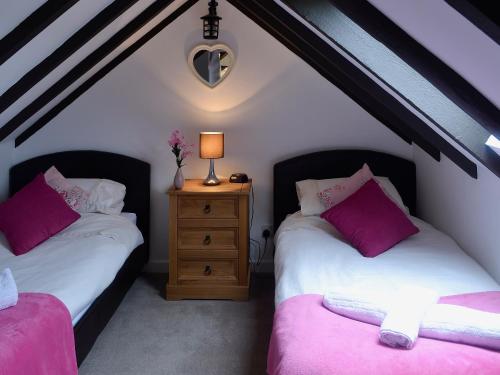 two twin beds in a attic room with a night stand at Wee Dug Hoose in Glenluce