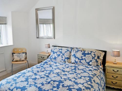 a bedroom with a blue and white bed and a chair at Tree Tops in Youlgreave