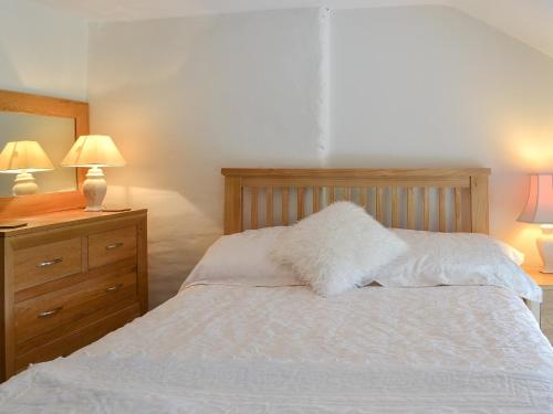 a bedroom with a white bed with two lamps and a dresser at Bryntrisant in Devils Bridge