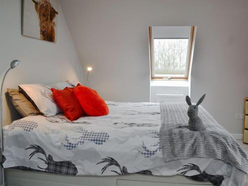 a bedroom with a bed with a comforter and red pillows at The Snug in Harthill