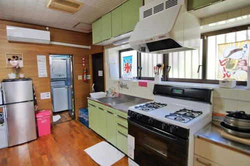 cocina con armarios verdes y fogones horno superior en Sunabe Beach House, en Hamakawa